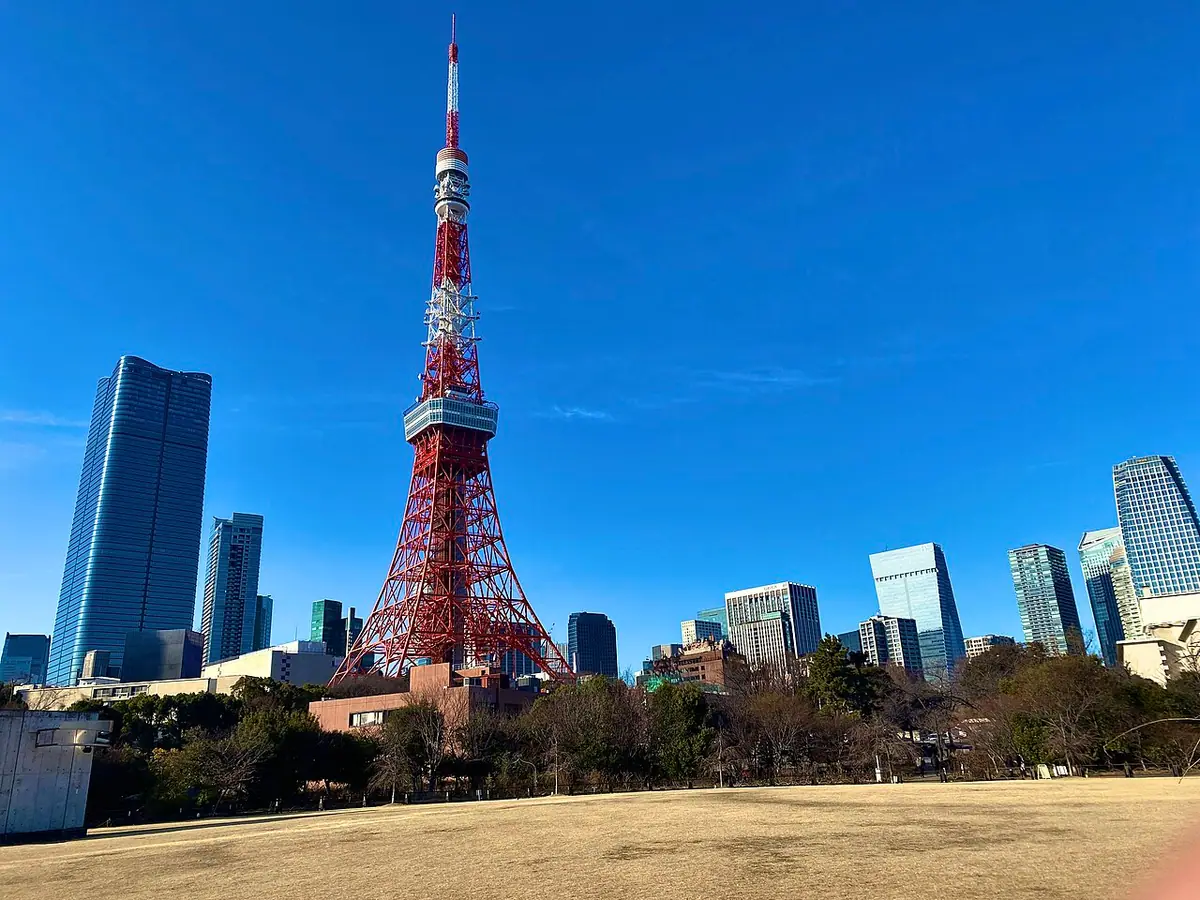 Tokyo Tower beyond the lawns of Shiba Park under a blue sky